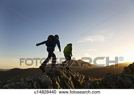 Stock Image - Men hiking on rocky mountainside. Fotosearch