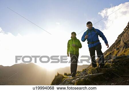 Stock Photo - Men hiking on rocky mountainside. Fotosearch