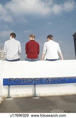 Stock Photo - Men sitting on rooftop wall. Fotosearch