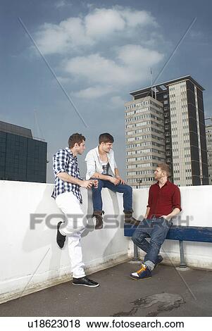 Stock Photo - Men talking on urban rooftop. Fotosearch