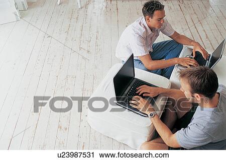 Men using laptops in living room View Large Photo Image Stock Image - Men using laptops in living room. Fotosearch