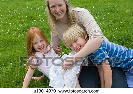 Mother and children playing in grass View Large Photo Image Stock Image - Mother and children playing in grass. Fotosearch