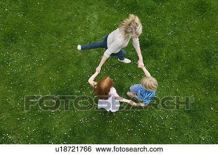 Stock Photograph - Mother and children playing in grass. Fotosearch