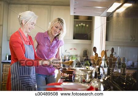 Stock Photo - Mother and daughter cooking in kitchen. Fotosearch
