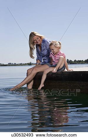 Mother and daughter relaxing on dock View Large Photo Image Stock Image - Mother and daughter relaxing on dock. Fotosearch