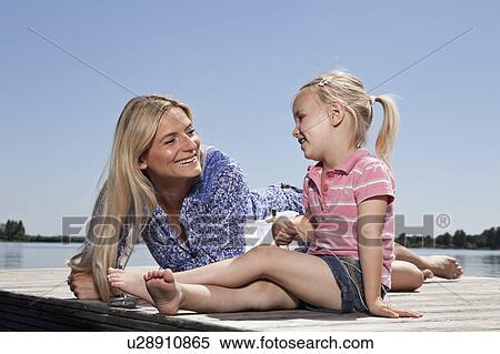 Stock Photography - Mother and daughter relaxing on dock. Fotosearch