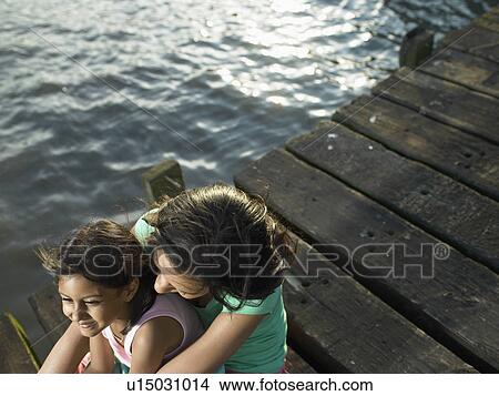 Mother and daughter sitting on dock View Large Photo Image Picture - Mother and daughter sitting on dock. Fotosearch