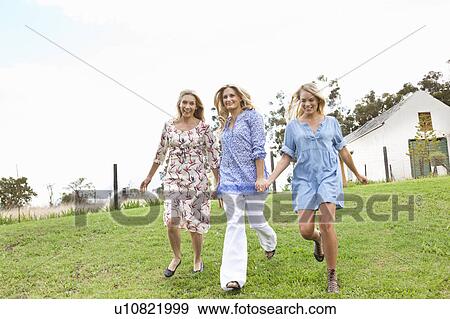Stock Photo - Mother and daughters running in garden. Fotosearch