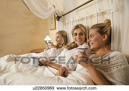 Stock Photo - Mother and daughters with coffee in bed. Fotosearch