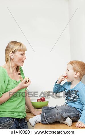 Stock Image - Mother and son eating apples together. Fotosearch