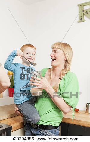 Stock Photograph - Mother and son eating in kitchen. Fotosearch