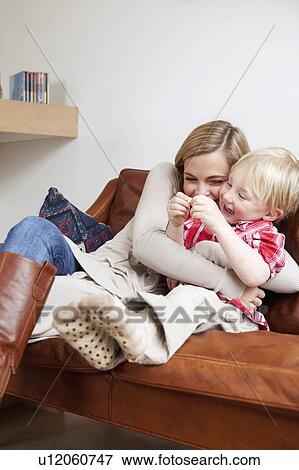 Stock Photo - Mother and son hugging on sofa. Fotosearch