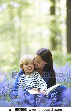Stock Photo - Mother and son reading in forest. Fotosearch