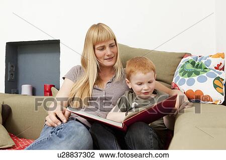 Stock Image - Mother and son reading together on sofa. Fotosearch