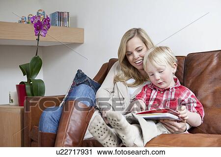 Mother and son sitting on sofa together View Large Photo Image Stock Image - Mother and son sitting on sofa together. Fotosearch