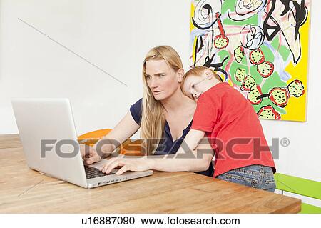 Stock Image - Mother and son using laptop together. Fotosearch