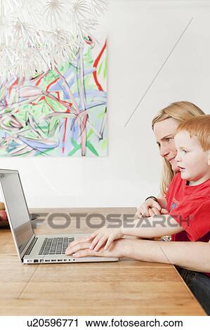 Stock Image - Mother and son using laptop together. Fotosearch