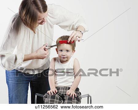 Stock Image - Mother cutting son’s hair. Fotosearch