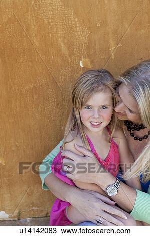 Stock Image - Mother embracing daughter outdoors. Fotosearch