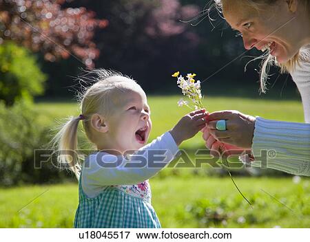 Stock Photo - Mother handing daughter bunch of flowers. Fotosearch