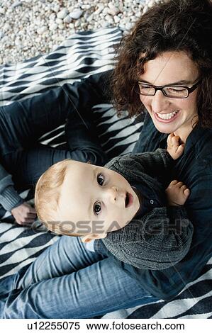 Stock Photography - Mother holding curious baby outdoors. Fotosearch