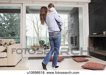 Mother holding son in living room View Large Photo Image Stock Photo - Mother holding son in living room. Fotosearch