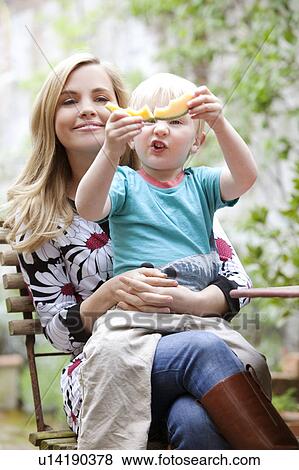 Stock Photo - Mother holding son with slice of melon. Fotosearch