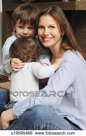 Mother hugging sons in living room View Large Photo Image Stock Photograph - Mother hugging sons in living room. Fotosearch