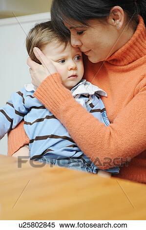 Stock Photography - Mother hugging toddler son at table. Fotosearch