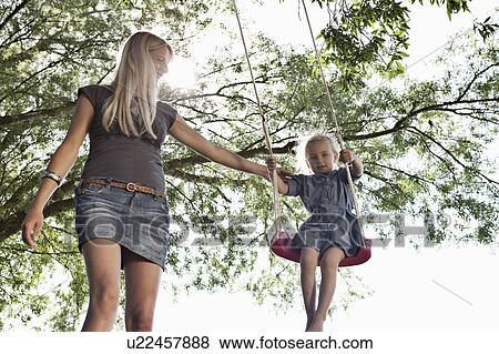 Mother pushing daughter on swing View Large Photo Image Stock Photo - Mother pushing daughter on swing. Fotosearch