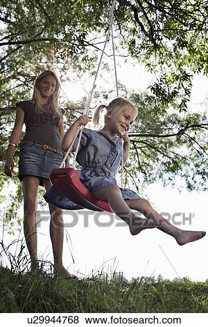 Mother pushing daughter on swing View Large Photo Image Stock Photo - Mother pushing daughter on swing. Fotosearch