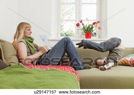 Mother relaxing as son jumps on sofa View Large Photo Image Stock Photo - Mother relaxing as son jumps on sofa. Fotosearch