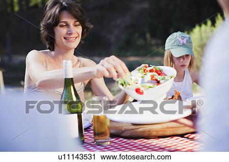 Mother serving salad at picnic View Large Photo Image Stock Image - Mother serving salad at picnic. Fotosearch