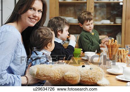 Stock Photograph - Mother sitting with sons at table. Fotosearch