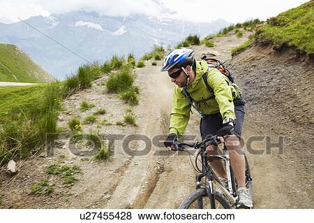 Stock Photo - Mountain biker on dirt road. Fotosearch
