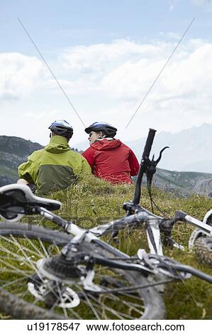 Stock Photo - Mountain bikers relaxing on hillside. Fotosearch