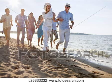 Stock Image - Newlywed couple on beach with friends. Fotosearch