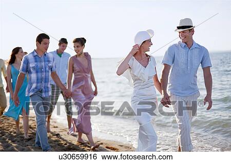 Stock Photograph - Newlywed couple on beach with friends. Fotosearch