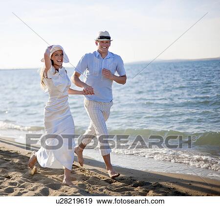 Stock Photo - Newlywed couple running on beach. Fotosearch