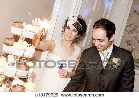 Newlywed couple with sparkler on cake View Large Photo Image Stock Photo - Newlywed couple with sparkler on cake. Fotosearch
