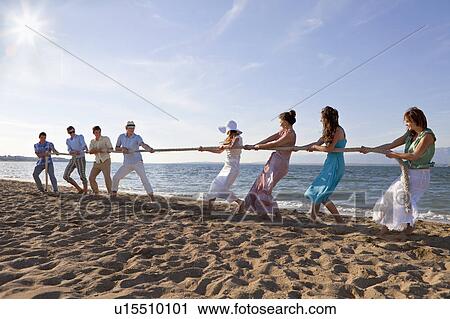 Stock Image - Newlyweds and guests playing tug of war. Fotosearch