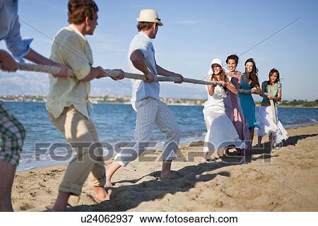 Stock Photo - Newlyweds and guests playing tug of war. Fotosearch
