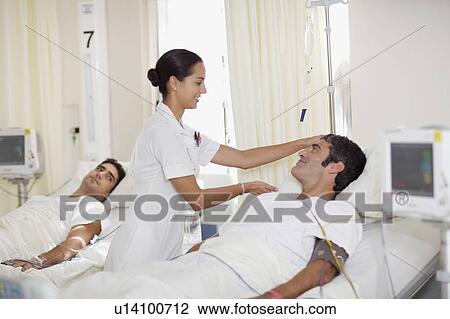 Nurse tending to patient in hospital bed View Large Photo Image Stock Image - Nurse tending to patient in hospital bed. Fotosearch