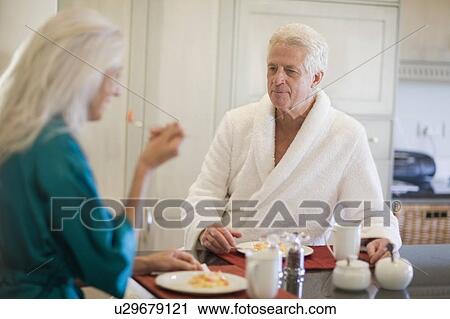 Stock Image - Older couple in bathrobes at breakfast. Fotosearch