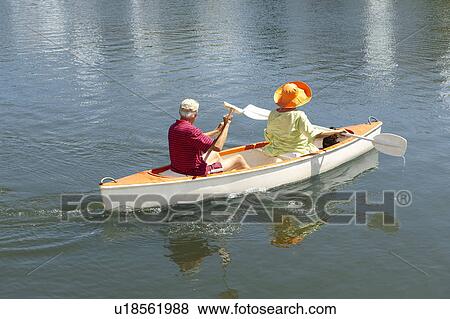 Stock Photo - Older couple rowing canoe on lake. Fotosearch