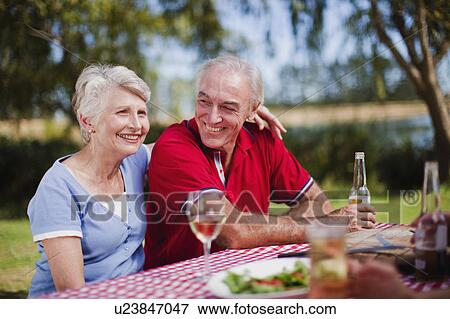 Older couple sitting at picnic table View Large Photo Image Stock Photo - Older couple sitting at picnic table. Fotosearch