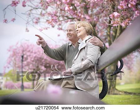 Older couple sitting on park bench View Large Photo Image Picture - Older couple sitting on park bench. Fotosearch