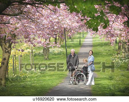 Stock Image - Older couple with caretaker in park. Fotosearch