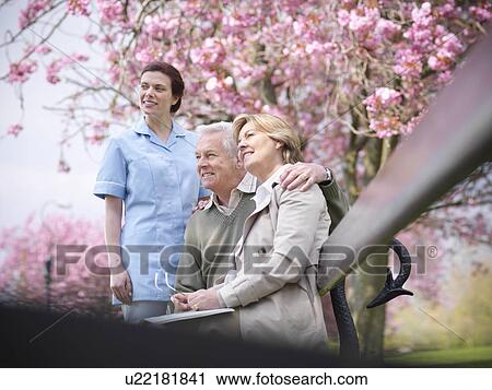 Older couple with caretaker in park View Large Photo Image Stock Image - Older couple with caretaker in park. Fotosearch