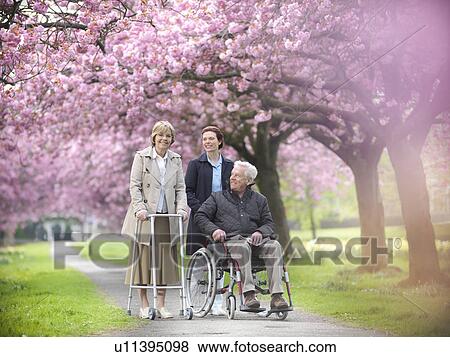 Stock Photo - Older couple with caretaker in park. Fotosearch